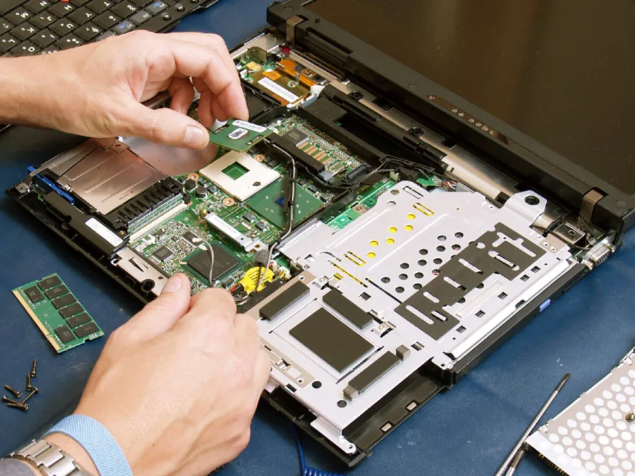 Técnico realizando conserto de notebook aberto em bancada especializada